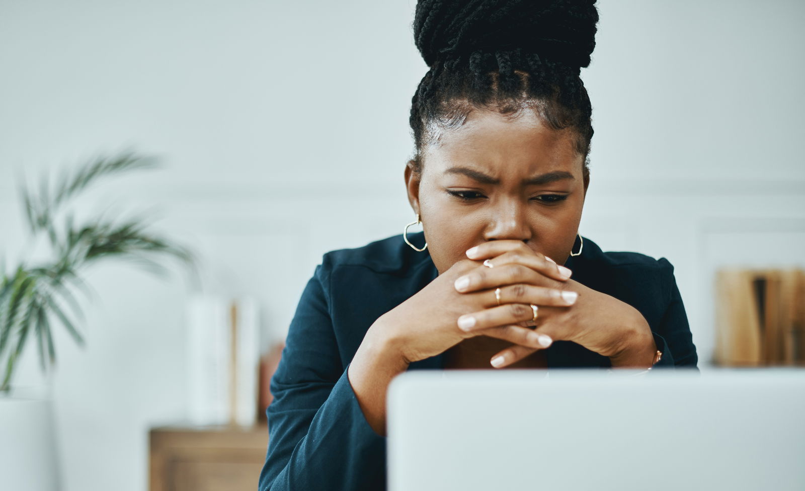 Shot of a young businesswoman frowning while using a laptop in a modern office